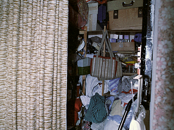 Die Stasi fotografierte die Privaträume von Bürgern. Zu sehen ist ein Schmaler Abstellraum, der bis oben mit Plastiktüten und Koffern gefüllt ist.