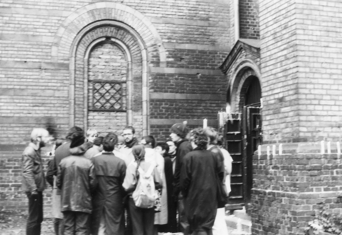 Ein Gruppe von Teilnehmern einer Mahnwache steht vor der Zionskirche. Sie protestieren gegen Festnahmen in der Umweltbibliothek Ende November 1987.