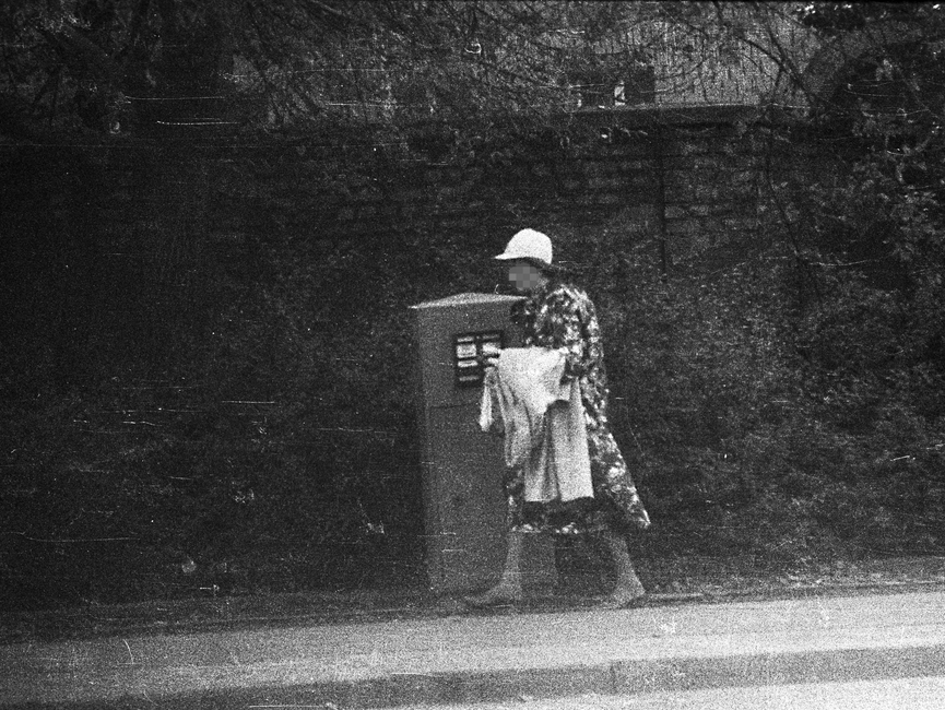 Stasi-Observation von Bürgern beim Einwurf von Post in einen öffentlichen Briefkasten. Hier geht eine ältere Dame am Briekasten vorbei.